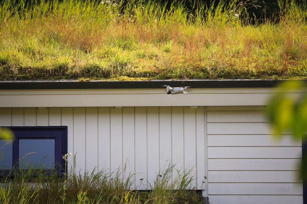 Drohne fliegt vor Haus mit Gründach